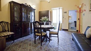 A dining area with a round table, chairs, a cabinet, and a patterned floor.