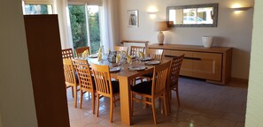 A dining area with a wooden table and chairs, a buffet counter, and a window with curtains.