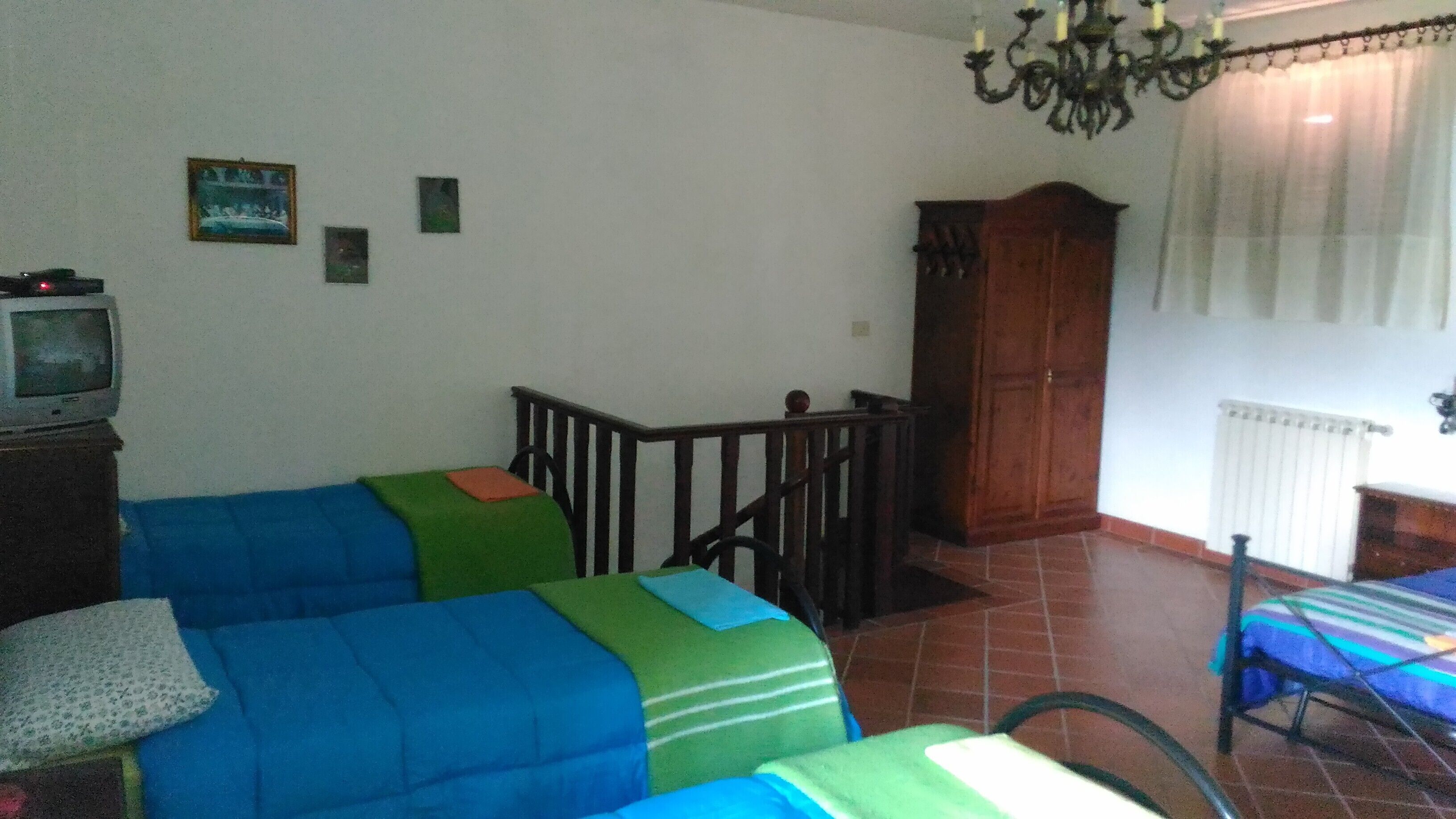 A room with two beds, a wooden cabinet, a television, and a staircase.