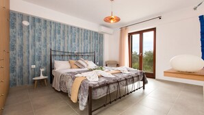 Una camera da letto con un letto, un piccolo tavolino, una panca, una grande finestra e un condizionatore d'aria.