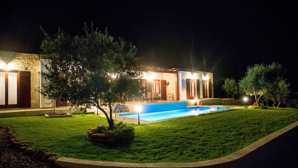 Una casa moderna con piscina, immersa in un prato curato e alberi.