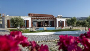 Una villa moderna con piscina, pareti in pietra e giardino.