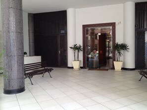 Eine Hotelhalle mit einer Rezeption, einer Bank und zwei Topfpflanzen.