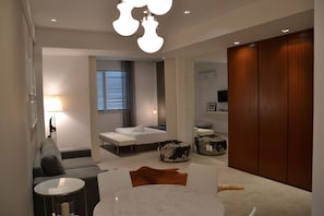 Ein modernes Wohnzimmer mit einer Couch, einem runden Couchtisch und einem außergewöhnlichen Hocker.