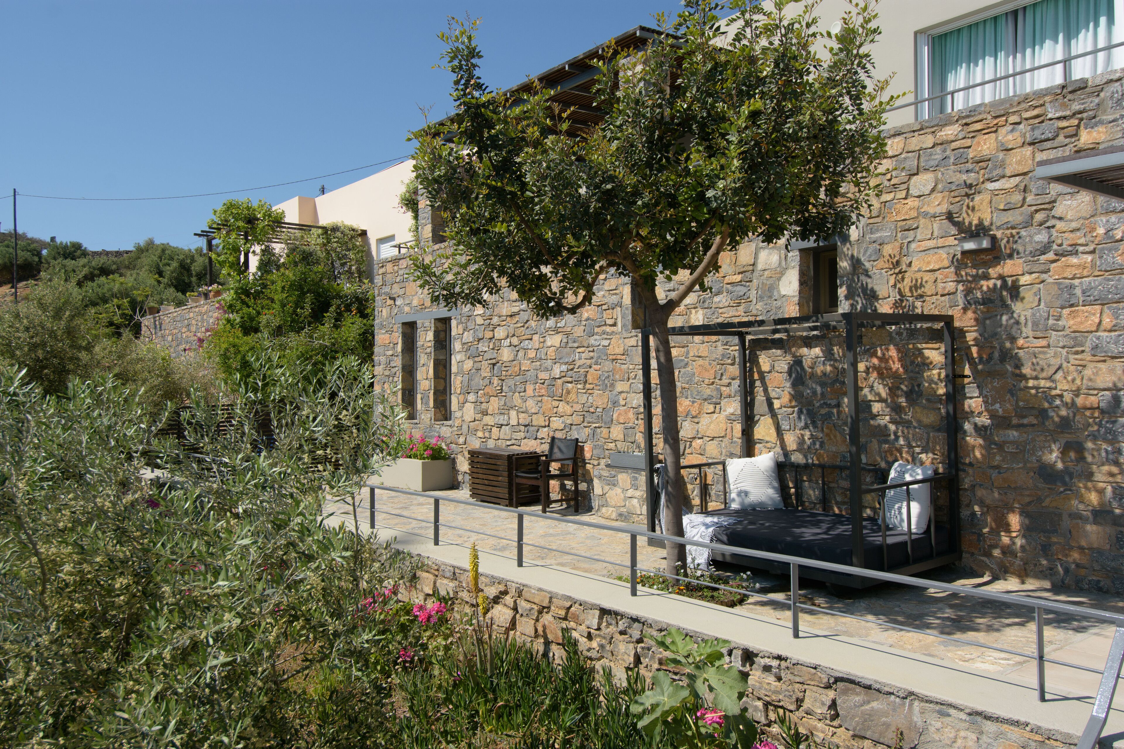 Un edificio de piedra con una pérgola y zona de estar al aire libre.