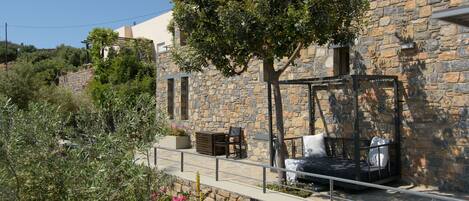 Un edificio de piedra con una pérgola y zona de estar al aire libre.