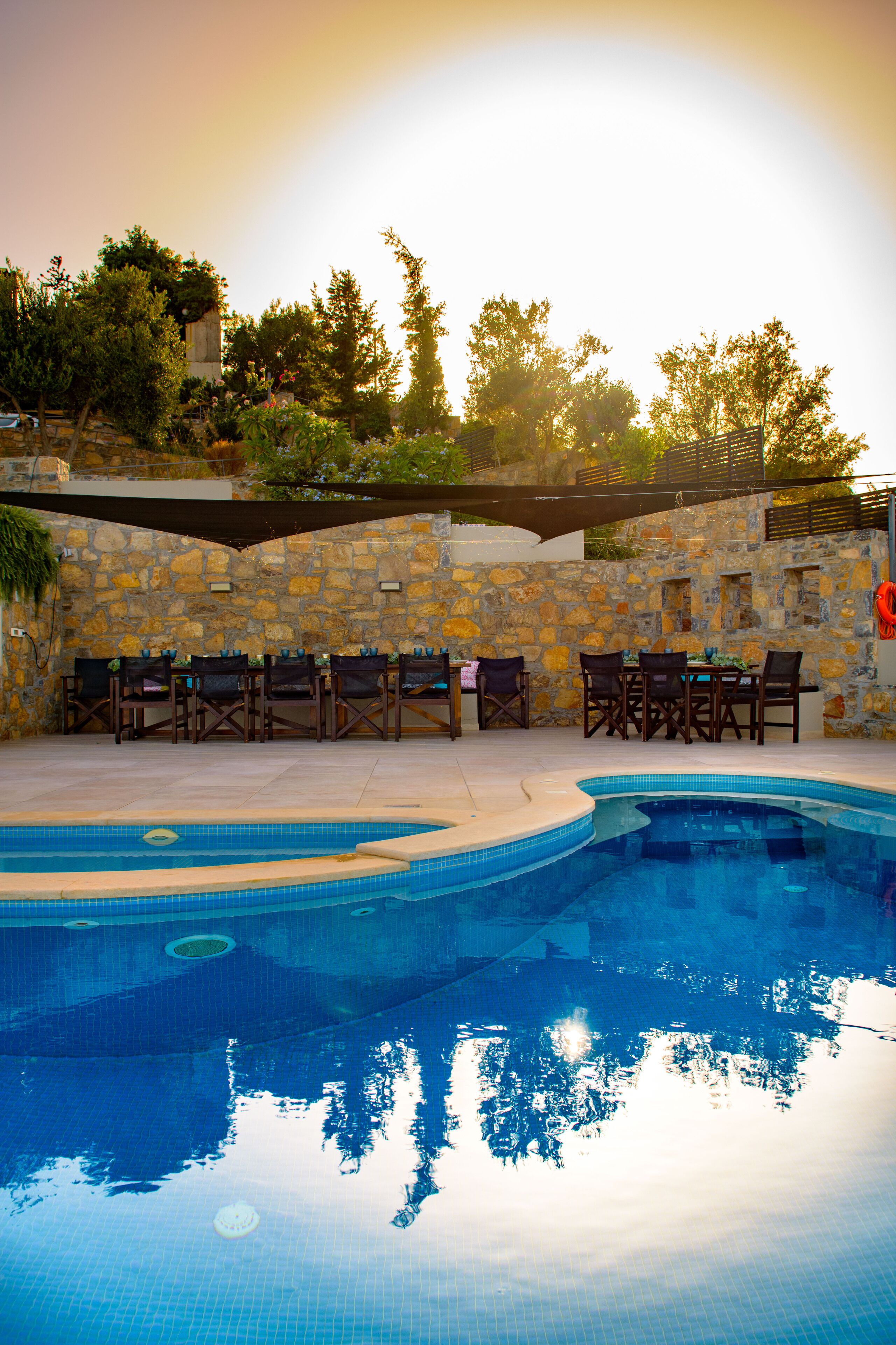 A swimming pool with lounge chairs and a stone wall.