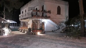 Un edificio con balcón, escalinata y entrada cubierta.