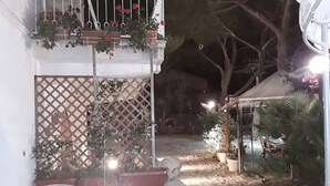 Un patio con plantas en macetas, una silla blanca y una pequeña mesa.