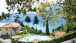 A residential property with a swimming pool, a house, and a view of a lake and mountains.