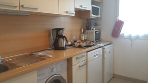 A compact kitchen with a washing machine, microwave, and a coffee maker. - Lovely Apartment in Nice - Book now for great Prices! (Nice)