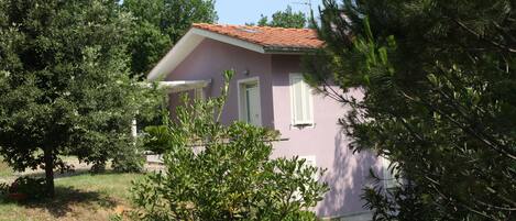 A small house with a red roof, surrounded by trees and greenery.