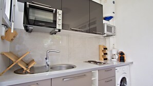 Een moderne keuken met een inbouwoven, magnetron, spoelbak en vaatwasser.