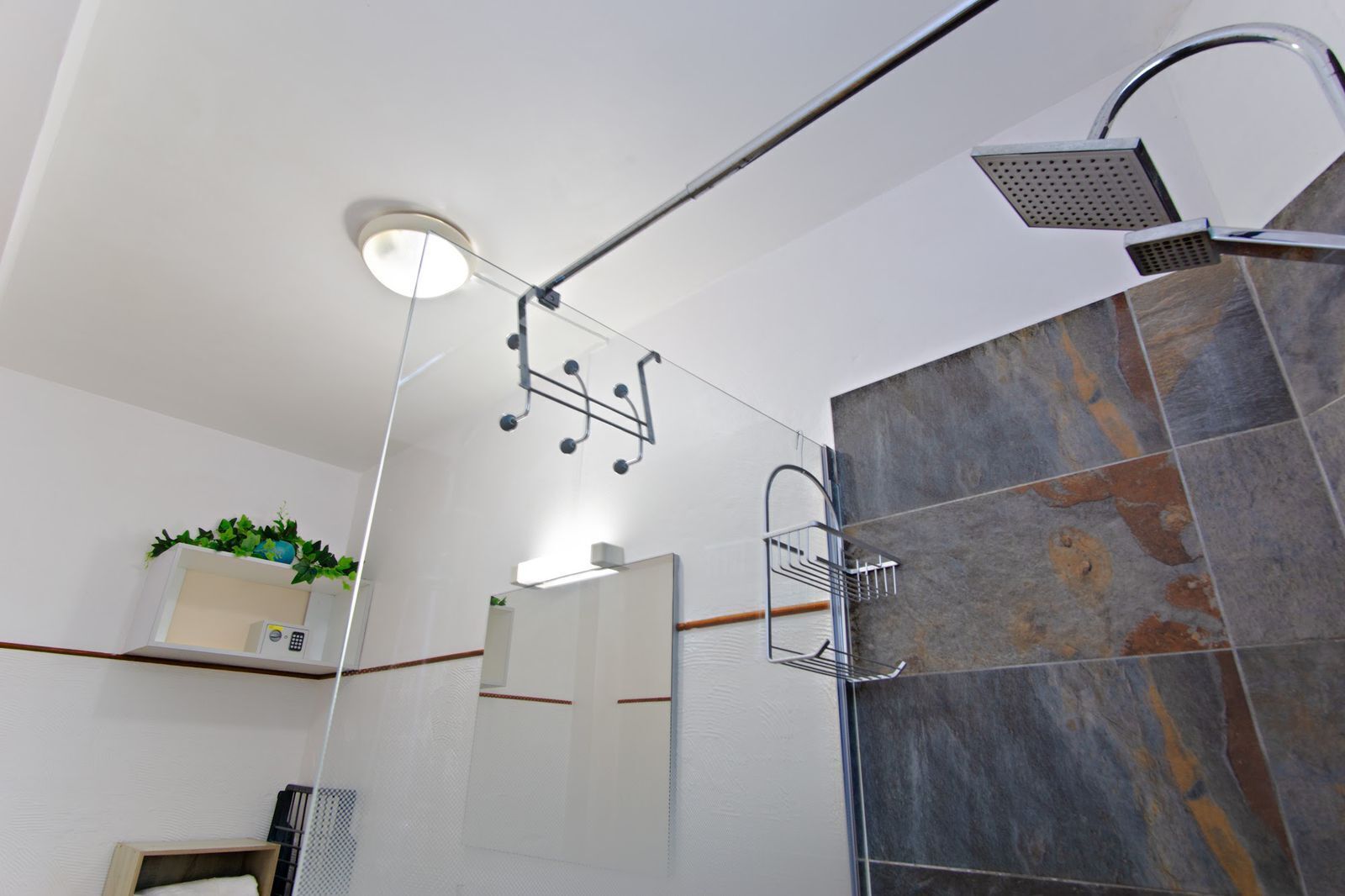 A modern bathroom with a shower, a built-in shelf with a microwave, and a mirror.