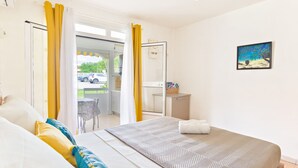 Een slaapkamer met een bed, nachtkastje, stoel en uitzicht.