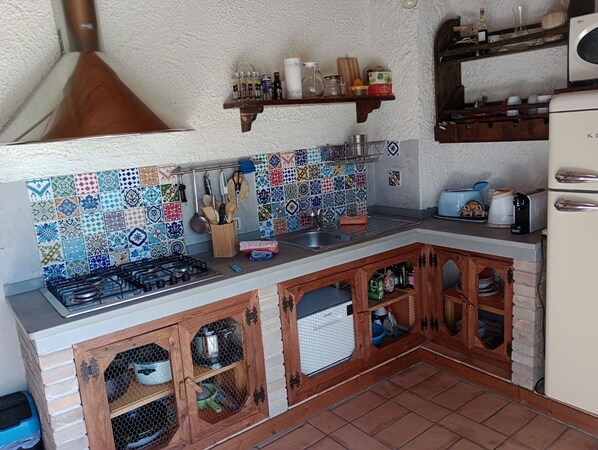 A kitchen with a tiled backsplash, wooden cabinets, a gas stove, and various kitchen utensils.