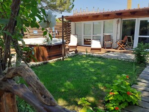 A patio area with a hot tub, wooden deck, and outdoor seating.