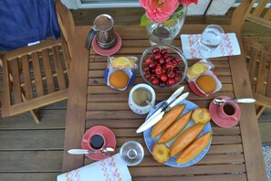 Una mesa de madera con diversos alimentos y bebidas, entre ellos cerezas, pan y una jarra de café.