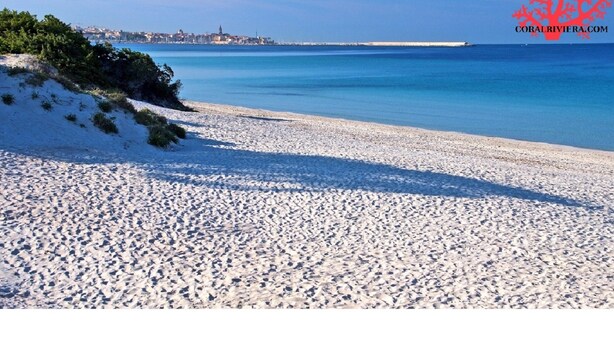 Ein Strand mit weißem Sand und blauem, klarem Wasser.