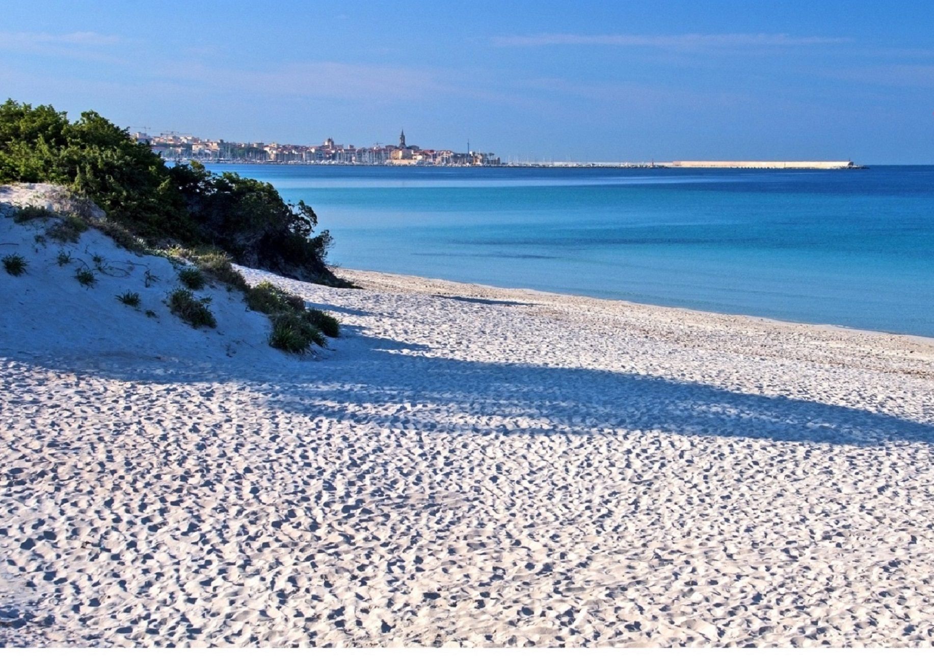 Une plage de sable blanc bordée par une mer d’un bleu limpide.