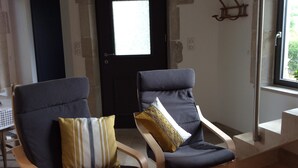 Two armchairs with cushions, a black door, a window, and a stone wall.