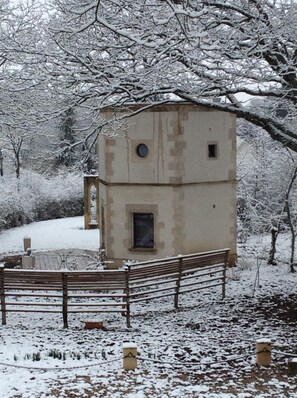 Un petit bâtiment à deux étages, de conception simple et rectangulaire, entouré d’arbres couverts de neige et d’une clôture en bois.