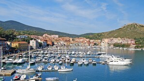 A marina with numerous boats docked, surrounded by buildings and hills in the background.