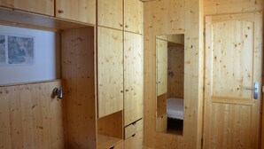 Ein Zimmer mit Holzboden, einem Bett, einem Kleiderschrank und einem Spiegel.