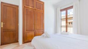 A bedroom with a large bed, wooden wardrobe, and a window with curtains. - ROSER (ROSER DE ARTÀ) - Townhouse with terrace in Artà. Free WiFi (Artà)