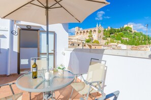 A balcony with a glass table, chairs, and an umbrella. A bottle and glasses are on the table. A door is visible in the background. - ROSER (ROSER DE ARTÀ) - Townhouse with terrace in Artà. Free WiFi (Artà)