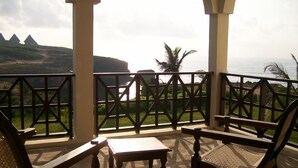 A balcony with a view of the ocean and hills. There are two wooden chairs and a small table. - Fantastic 3 bedroom Penthouse apartment overlooking the Indian Ocean. (Watamu)