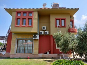 A two-story building with a red and yellow facade, multiple windows, and air conditioning units. -  Perfect location 2 minutes to all amenities, bars/bus/restaurants and shops. (Ölüdeniz)