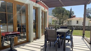 Une terrasse couverte avec une table et des chaises pour les repas, une table de billard et une vue sur le paysage environnant.