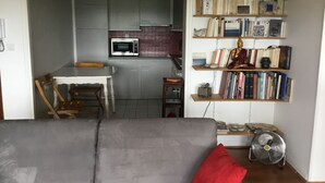 A compact living space with a kitchenette, a dining area, and a bookshelf filled with books and decorative items. - Pau facing the Pyrenees (Pau)
