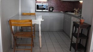A compact kitchen with a white table, wooden chairs, a microwave, and a sink. - Pau facing the Pyrenees (Pau)