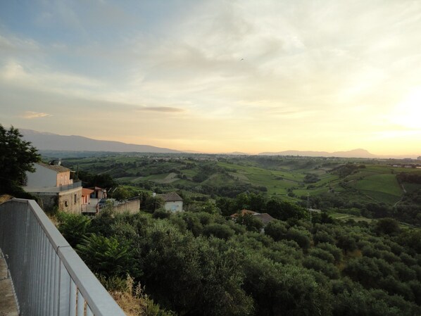 A rural landscape with rolling hills and a few buildings.