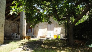 A courtyard with a brick building, a tree, and outdoor furniture.