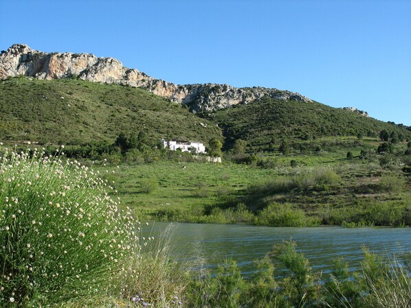 Una casa en una colina con un lago al frente.