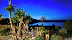 A garden with a hammock, palm trees, and a view of a lake at night. - Refurbished holiday apartment in an Andalusian farmhouse in The Lake District (Antequera)