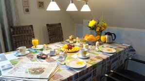 Ein Frühstückstisch ist gedeckt mit Tellern, Gläsern und einer Zeitung.