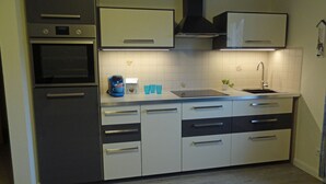 Eine moderne Küche mit Edelstahlgeräten, weißen Schränken und einem eingebauten Backofen.