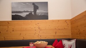 A wooden bench with a bowl of snacks and a candle, a red pillow, and a wall-mounted picture of a hiker. - 55m² large apartment with terrace and garden and separate entrance (Hippach)