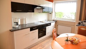 Una cocina moderna con horno integrado, cafetera y ventana con vistas al verdor.