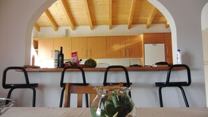 A dining area with a table set for four, a vase with decorative stones and a starfish, and wooden cabinets in the background.