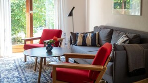 Ein Wohnzimmer mit einer Couch, zwei roten Sesseln, einem Couchtisch und einer Stehlampe.