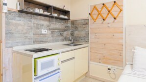 Una cocina compacta con microondas integrado, un lavamanos y estantes de madera.