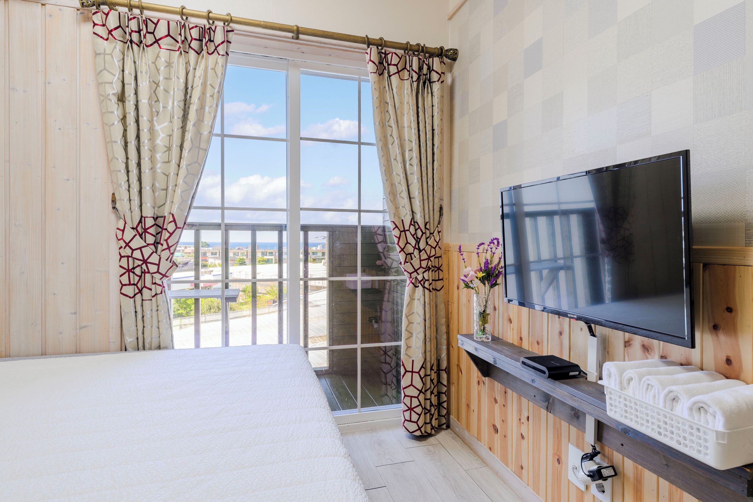 Une chambre d’hôtel avec un grand lit, une télévision, un mur en bois et un balcon avec vue.