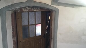 Un couloir étroit avec une porte en bois dotée de panneaux en verre dépoli.