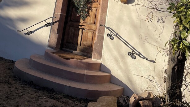 Une maison avec une porte en bois, une petite fenêtre et un toit recouvert de tuiles.