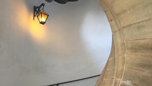 Un escalier en colimaçon avec une main courante en pierre et un luminaire fixé au mur.